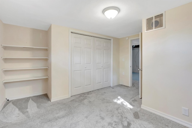 unfurnished bedroom with carpet floors, baseboards, visible vents, and a closet