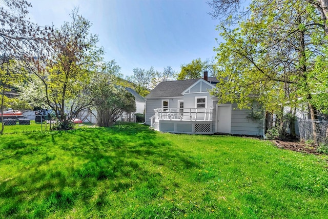rear view of property featuring a yard, a deck, fence, and a chimney