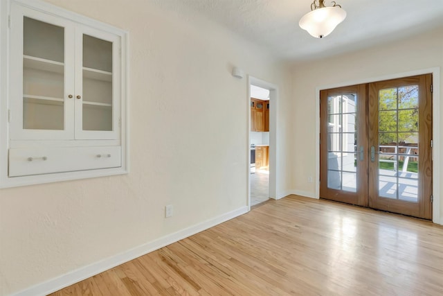 entryway with french doors, baseboards, and light wood finished floors