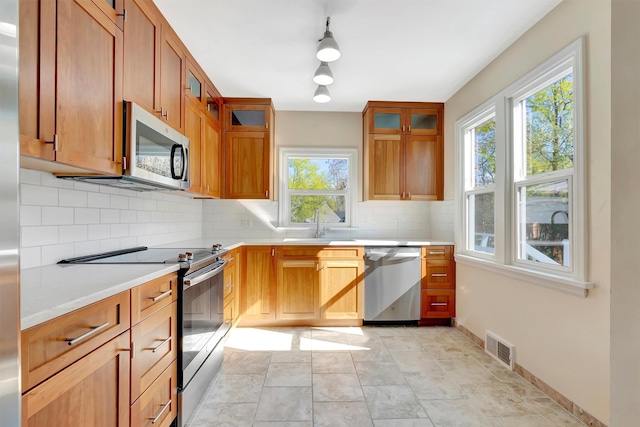 kitchen featuring backsplash, appliances with stainless steel finishes, plenty of natural light, and visible vents