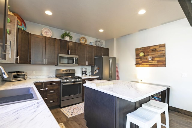kitchen featuring a center island, a breakfast bar, stainless steel appliances, and dark wood-type flooring