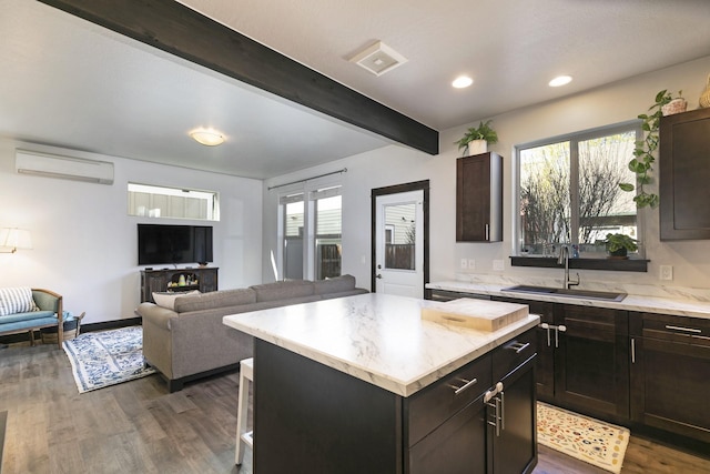 kitchen featuring beam ceiling, a sink, a breakfast bar area, an AC wall unit, and dark wood-type flooring