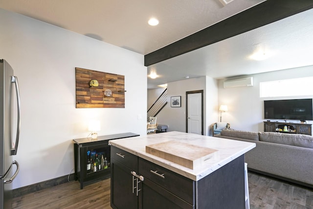 kitchen featuring beam ceiling, freestanding refrigerator, an AC wall unit, dark wood-style floors, and open floor plan