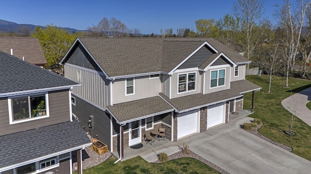 view of front of home featuring roof with shingles, an attached garage, driveway, and a front lawn