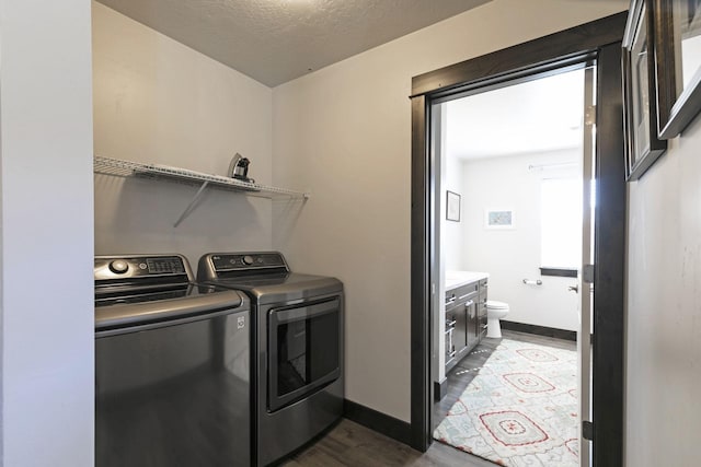laundry room featuring laundry area, baseboards, dark wood-style floors, a textured ceiling, and washing machine and clothes dryer