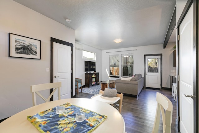 dining room with dark wood-style flooring, a textured ceiling, and a wealth of natural light