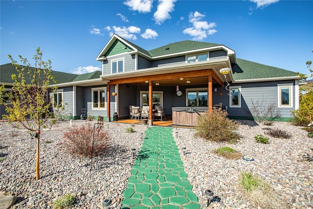 rear view of house featuring a hot tub and roof with shingles