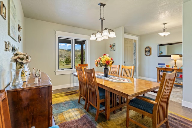 dining area with baseboards, a chandelier, and dark wood-type flooring