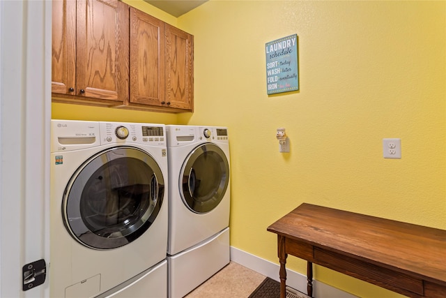 washroom with baseboards, cabinet space, and washer and dryer