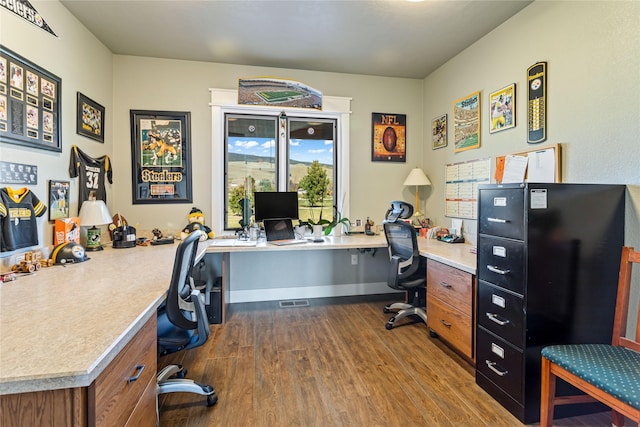 office space featuring dark wood-style flooring, baseboards, and built in desk