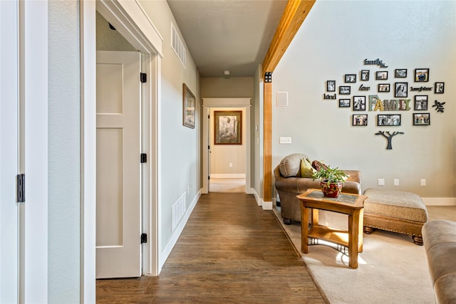 corridor featuring baseboards, dark wood finished floors, and visible vents