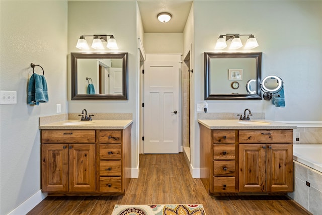 bathroom featuring a sink, wood finished floors, and two vanities