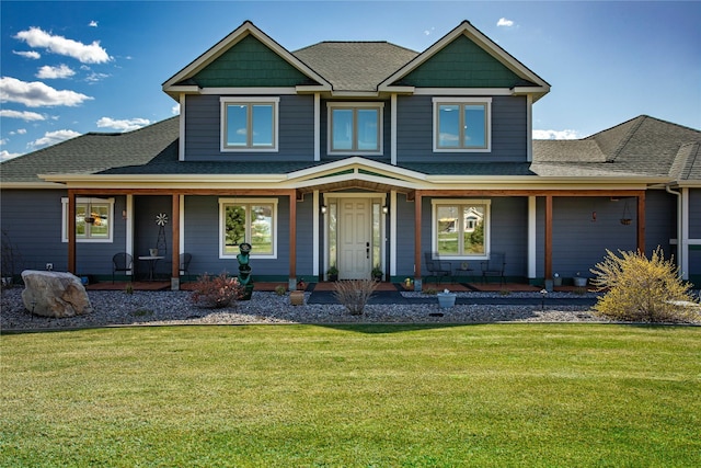 view of front of home featuring roof with shingles, covered porch, and a front lawn