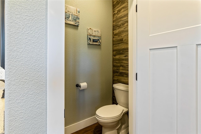 bathroom with baseboards, a textured wall, toilet, and wood finished floors