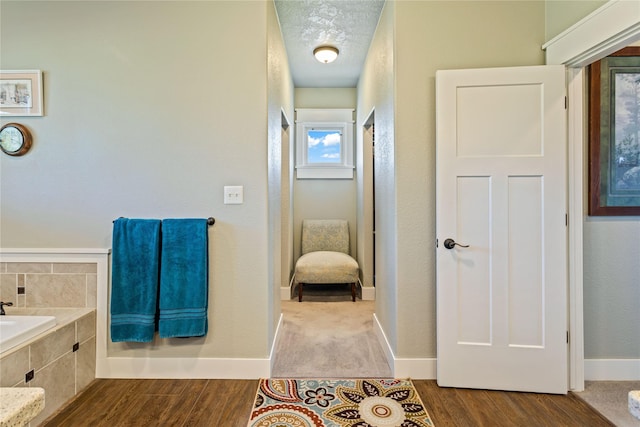 full bathroom with baseboards, tiled tub, and wood finished floors