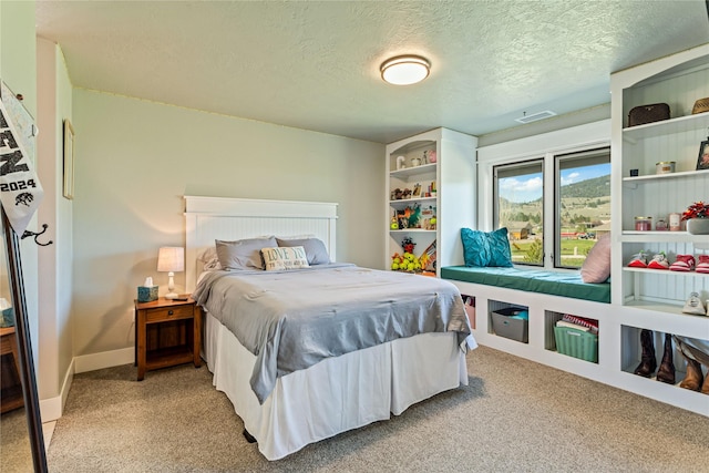 carpeted bedroom featuring a textured ceiling, visible vents, and baseboards