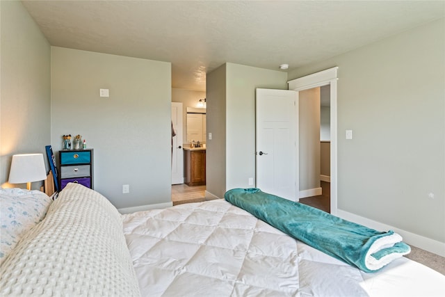 bedroom featuring connected bathroom, baseboards, and carpet floors