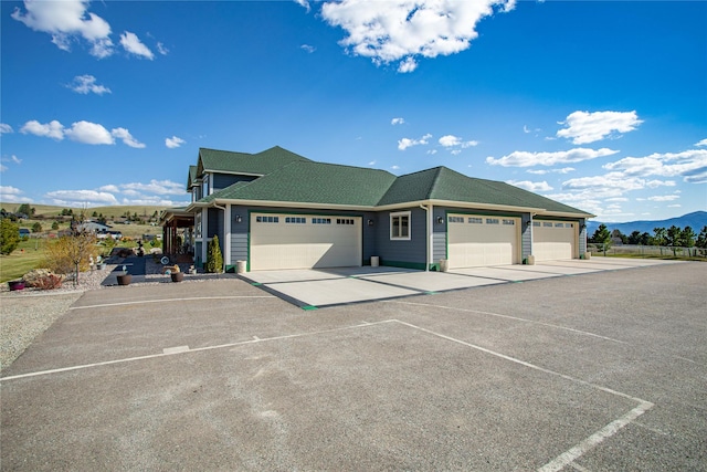 ranch-style home featuring roof with shingles, a mountain view, and a garage