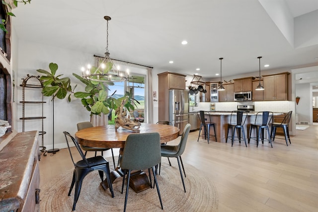 dining space with light wood-style floors, recessed lighting, and a notable chandelier