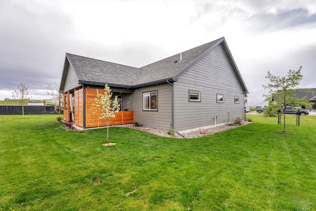 view of side of home featuring a shingled roof and a yard
