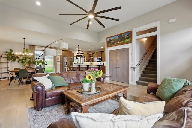 living area featuring recessed lighting, ceiling fan with notable chandelier, stairs, and light wood-style flooring