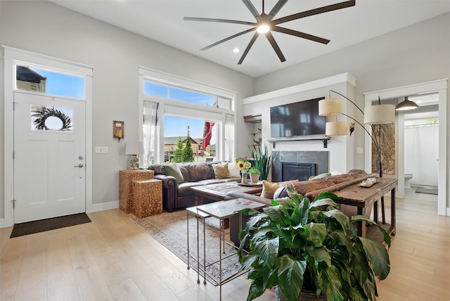 living room with ceiling fan, a fireplace, light wood-style flooring, recessed lighting, and baseboards