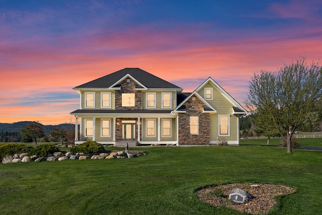 view of front of property featuring a lawn, covered porch, and stone siding