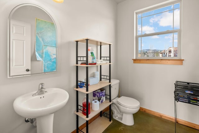 half bathroom with toilet, baseboards, concrete flooring, and plenty of natural light