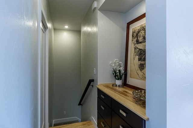 hall with wood finished floors and an upstairs landing