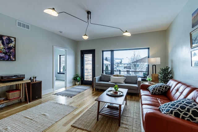 living area with baseboards, wood finished floors, and visible vents