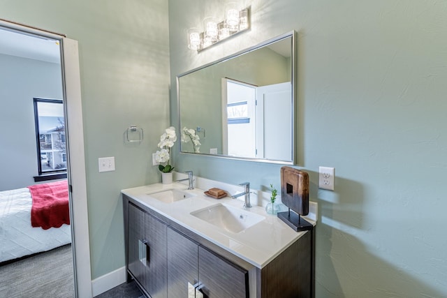 full bathroom with double vanity, a sink, baseboards, and ensuite bathroom