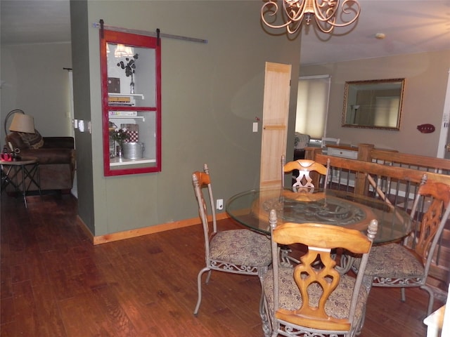 dining room featuring an inviting chandelier, a barn door, baseboards, and wood finished floors