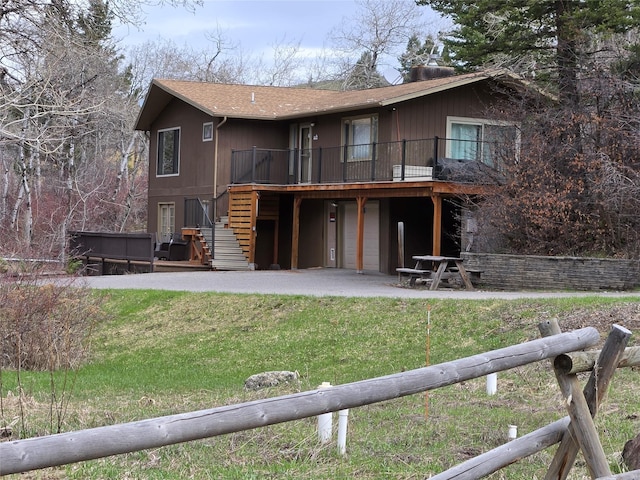 rear view of property with stairs, a shingled roof, a wooden deck, and a yard