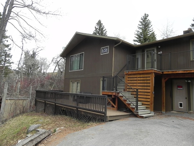 rear view of property with stairs and a wooden deck