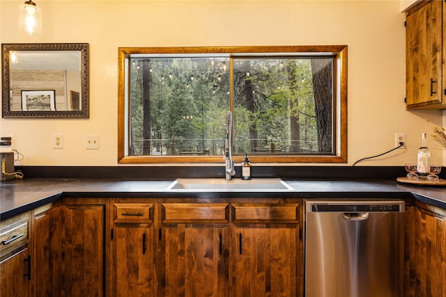 kitchen featuring stainless steel dishwasher, dark countertops, and a sink