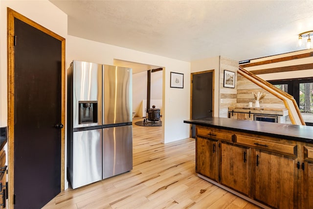 kitchen featuring dark countertops, stainless steel fridge with ice dispenser, and light wood-style floors