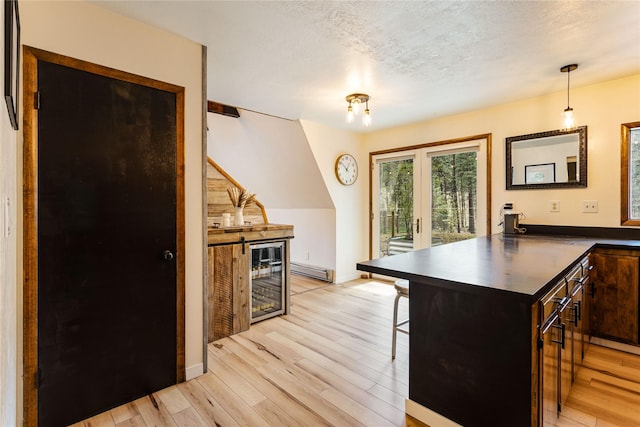 kitchen featuring a kitchen breakfast bar, dark countertops, light wood-type flooring, a baseboard heating unit, and a peninsula