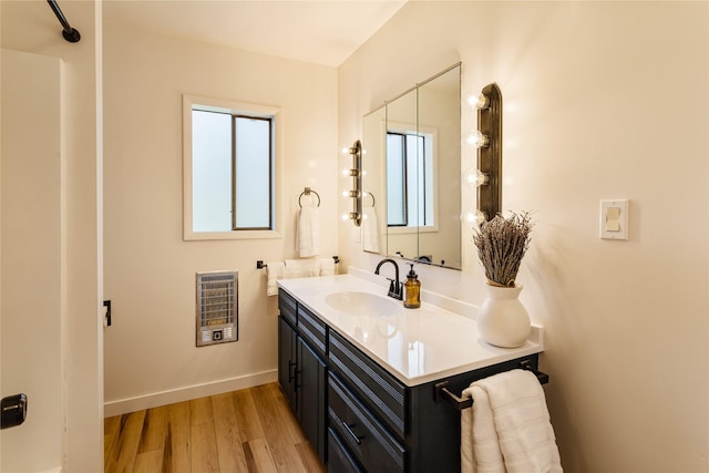 bathroom with baseboards, heating unit, wood finished floors, and vanity