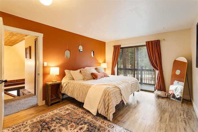 bedroom with access to exterior and wood finished floors