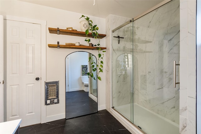 bathroom with heating unit, a marble finish shower, baseboards, and toilet