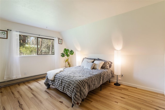 bedroom with wood-type flooring, baseboards, baseboard heating, and vaulted ceiling