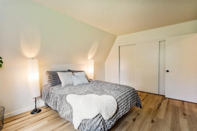 bedroom featuring vaulted ceiling, wood finished floors, and a closet