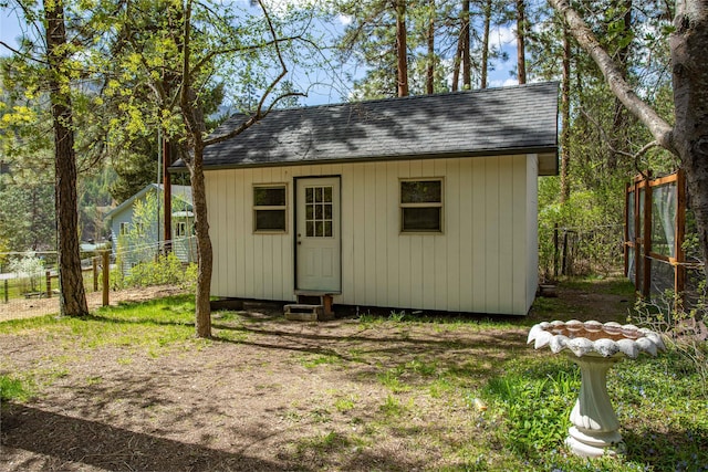 view of outdoor structure with fence and an outbuilding
