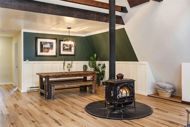 interior space featuring a decorative wall, baseboard heating, a wood stove, and light wood-style floors