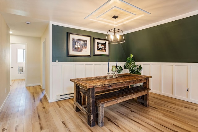 dining area with light wood-type flooring, a decorative wall, and a baseboard heating unit