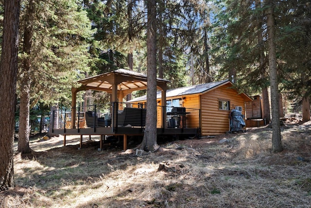 exterior space featuring a gazebo, a wooden deck, faux log siding, and metal roof