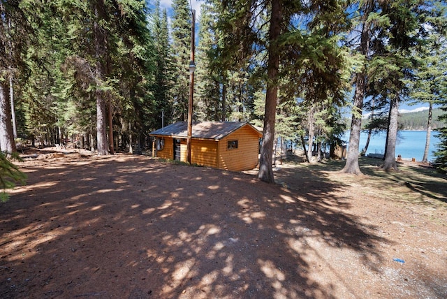 view of property exterior featuring an outbuilding, a water view, and faux log siding