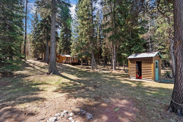 view of yard with a view of trees, an outbuilding, and a shed