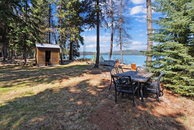 view of yard with an outdoor structure, a water view, and a shed