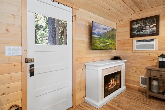 doorway to outside with wood finished floors, wooden walls, wood ceiling, a wall unit AC, and vaulted ceiling